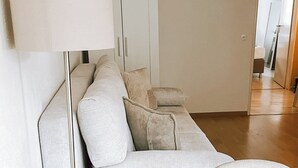 Ein modernes Wohnzimmer mit einem hellen Sofa, einer Stehlampe und einem Couchtisch aus Holz.