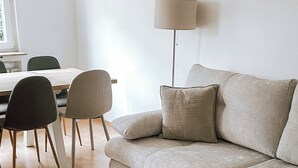 Ein modernes Wohnzimmer mit einer Couch, zwei Sesseln, einer Lampe und einem Esstisch.