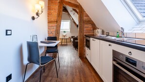 A kitchen with a skylight, wooden beams, and a dining area with a table and chairs. - "Suite Heimat" with King-Size Bed and Air Conditioning (Gengenbach)