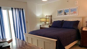 Een slaapkamer met een bed, nachtkastje, lamp en een raam met gordijnen.