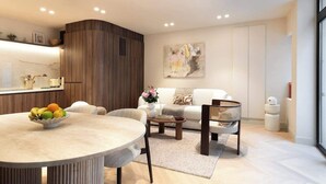 A modern living room with a round dining table, a sofa, and a coffee table. There is a kitchen area with a wooden cabinet and a countertop. - A Sophisticated 1-BR with Services - Louvre (Paris)