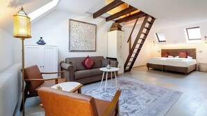 A loft-style room with a high ceiling, exposed wooden beams, a loft bed, a sofa, a coffee table, and a floor lamp. - "Suite Marrakesch" with King-Size Bed and Air Conditioning (Gengenbach)