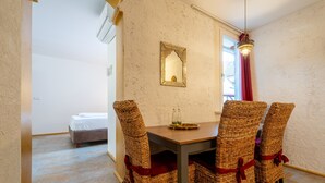 A dining area with wicker chairs, a wooden table, and a mirror on the wall. - "Suite Marrakesch" with King-Size Bed and Air Conditioning (Gengenbach)