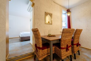 Ein Essbereich mit Korbstühlen, einem Holztisch und einem Spiegel an der Wand.