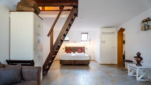 A bedroom with a bed, a wardrobe, a staircase, and a small table with a decorative item. - "Suite Marrakesch" with King-Size Bed and Air Conditioning (Gengenbach)