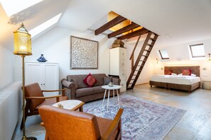 A loft-style bedroom with a sloped ceiling, a wooden ladder, a bed, a sofa, a coffee table, and a floor lamp. - "Suite Marrakesch" with King-Size Bed and Air Conditioning (Gengenbach)