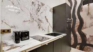 Una cocina moderna con salpicadero de mármol, encimera negra, un lavabo y una cafetera.