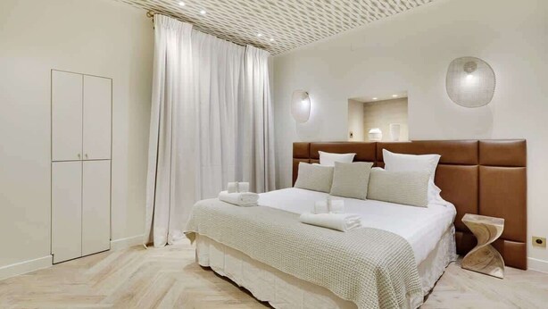 Un dormitorio moderno con una cama grande, un armario y un espejo en la pared.