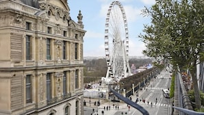 Un bâtiment historique à l’architecture riche et élaborée, avec une grande roue en arrière-plan.