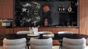 Un espace repas moderne avec un mur en marbre noir, un meuble en bois et une table à manger noire, accompagnée de quatre chaises.
