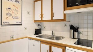 A kitchen with white cabinets, a stainless steel sink, a Samsung microwave, and a dishwasher. - An Exceptional 1-BR au Quai des Orfèvres (Paris)