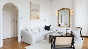 A modern living room with a white sofa, a round coffee table, and two chairs. - An Exceptional 1-BR au Quai des Orfèvres (Paris)