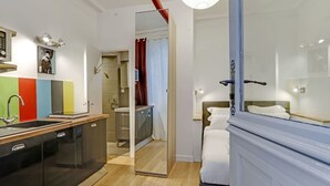 A modern bedroom with a large bed, a bedside table, and a wardrobe. - A Sweet Studio in Montparnasse (Paris)