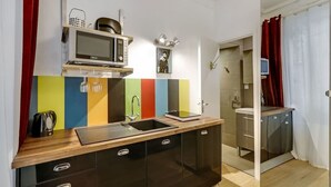 A modern kitchen with a microwave, sink, and cabinets. - A Sweet Studio in Montparnasse (Paris)