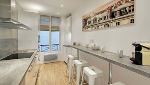 Una cocina moderna con un amplio ventanal, una campana extractora de acero inoxidable y una cafetera.