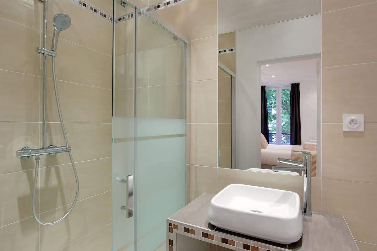 A modern bathroom with a glass shower enclosure, a white sink, and a mirror.