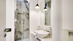 Une salle de bain moderne avec une douche à parois de verre, un lavabo blanc et un grand miroir.