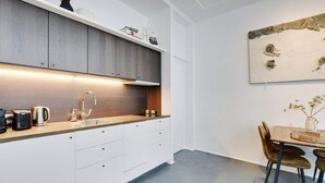 Une cuisine moderne avec des meubles blancs, un plan de travail en bois et un coin repas comprenant une table et des chaises.