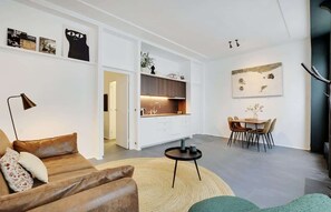 Uma sala de estar moderna com sofá, mesa de centro e área de jantar com cadeiras e mesa.