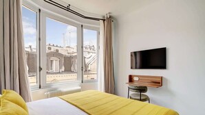 A hotel room with a bed, a TV, and a window with curtains. - A Majestic 2-BR/2Ba w/ Services in Opera-St-Lazare (Paris)