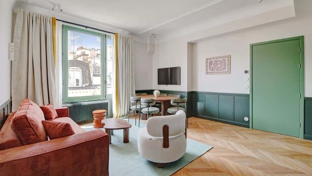 A modern living room with a sofa, armchair, and dining table. - A Majestic 2-BR/2Ba w/ Services in Opera-St-Lazare (Paris)