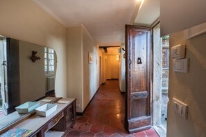 A hallway with a wooden door, a mirror, and a bench.