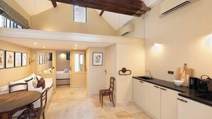 A spacious kitchen with a dining area, featuring a wooden dining table, chairs, a kitchen island, and a built-in oven. - A Charming 2-BR/2Ba in Saint Germain (Paris)