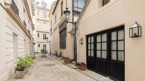 A narrow cobblestone alley with buildings on either side, potted plants, and a black door with a window. - A Charming 2-BR/2Ba in Saint Germain (Paris)