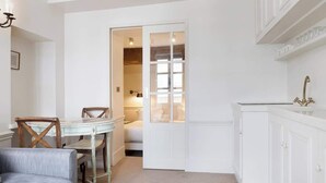 A compact room with a dining table, chairs, a sofa, a white cabinet, and a wardrobe. - French Chic Apartment in Saint Germain #1 (Paris)