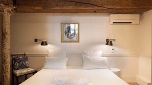 A hotel room with a large bed, two bedside lamps, a chair, and a framed mirror on the wall. - French Chic Apartment in Saint Germain #1 (Paris)