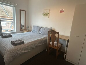 A bedroom with a bed, a wooden chair, a desk, a mirror, a nightstand, and a wardrobe. - Luton Homestay near AIRPORT  (Luton)