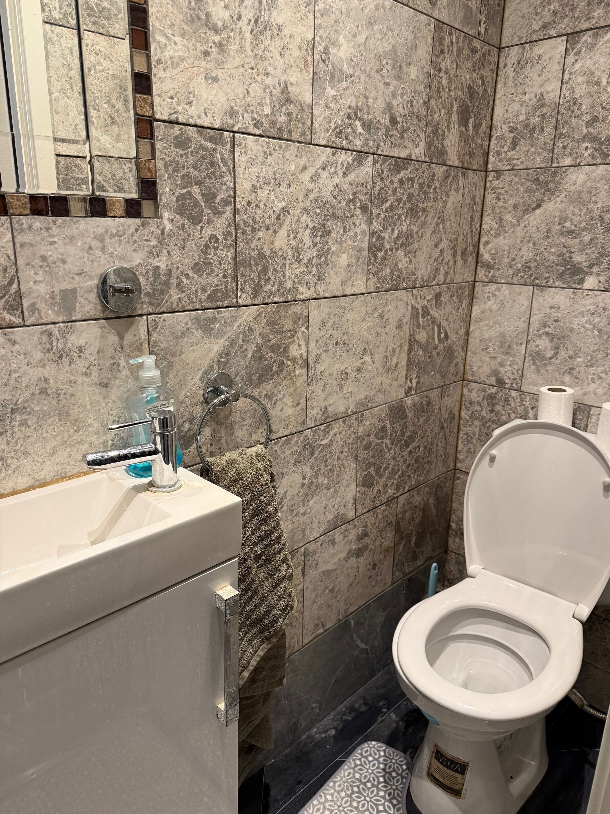 A bathroom with a white sink, a towel rack with a towel, a toilet, and a shower area.