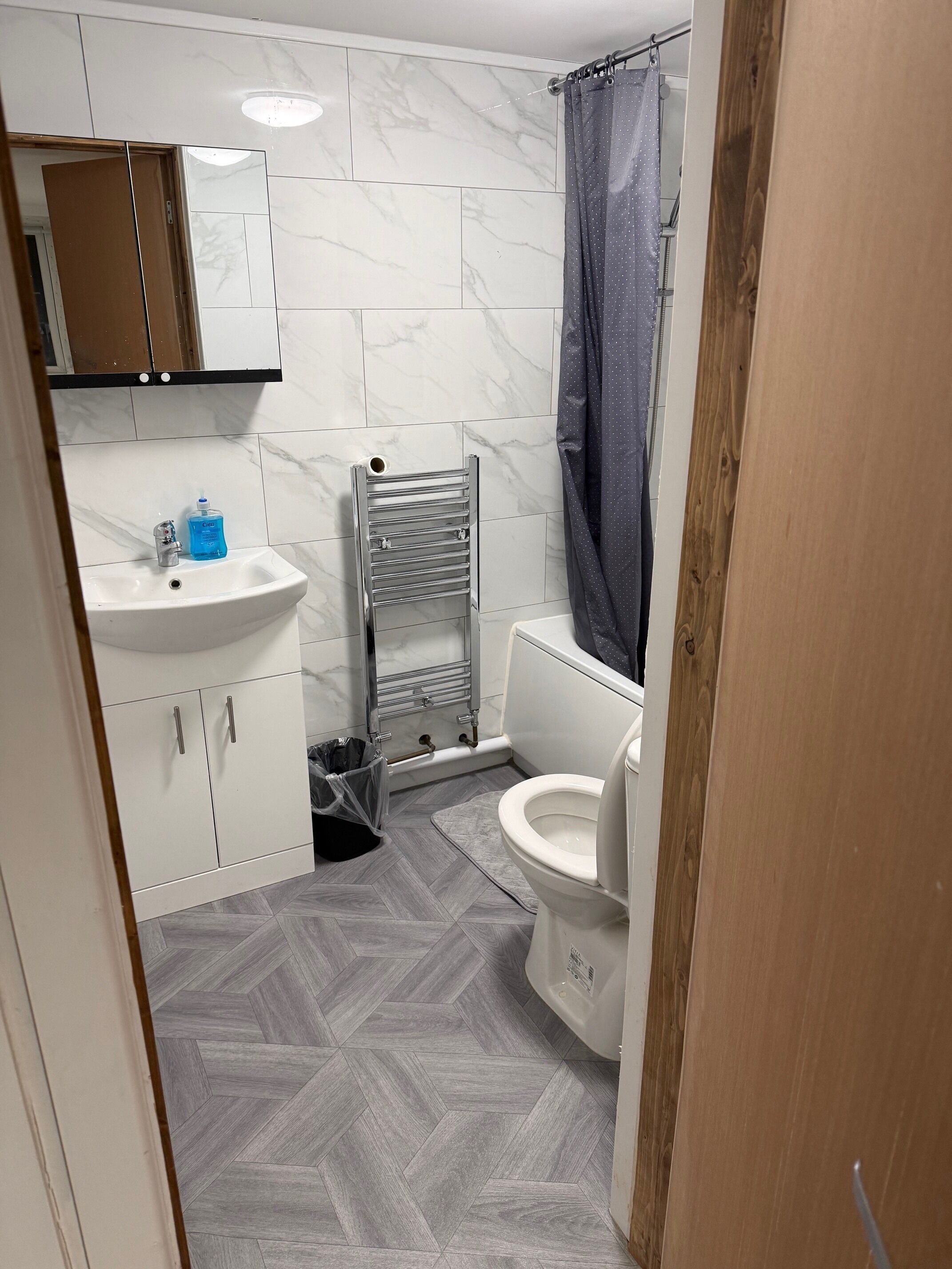 A bathroom with a white sink, a toilet, a towel rack, and a shower curtain.