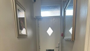 A narrow hallway with a white door, a radiator, a doormat, and a framed picture on the wall. - Luton Homestay near AIRPORT  (Luton)