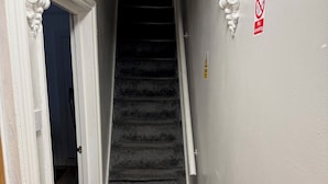 A staircase with a carpeted landing and a no-smoking sign on the wall. - Luton Homestay near AIRPORT  (Luton)