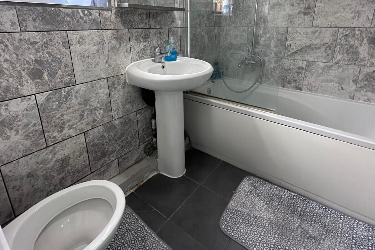 A bathroom with a toilet, sink, and shower area.
