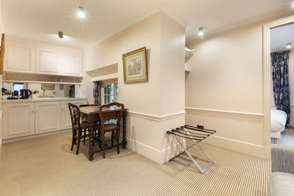 Une pièce comprenant une table à manger et des chaises, un portant à vêtements et un lit agrémenté d’un rideau à motifs bleus.