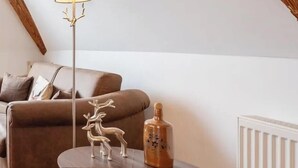 Un salón acogedor con un sofá marrón, una mesa redonda con una lámpara y un radiador.