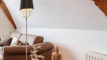 Ein gemütliches Wohnzimmer mit einem braunen Sofa, einem runden Holztisch, einer Stehlampe und einer Heizung.