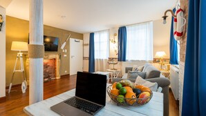 Una sala moderna con una laptop sobre una mesa, una chimenea, un sofá y un comedor con una lámpara.
