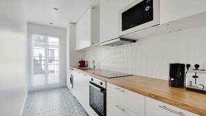 Eine moderne Küche mit weißen Schränken, einer Holzausziehtafel, einer eingebauten Mikrowelle, einer Kaffeemaschine und einem Toaster.