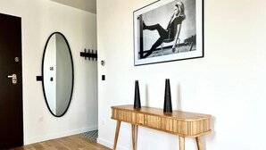 Ein Flur mit einem Holzkonsolentisch, einem Spiegel in Schwarzrahmen und einem gerahmten Foto an der Wand.