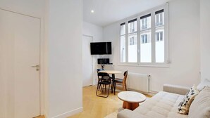 Un appartement moderne comprenant un espace de vie, un coin repas et un téléviseur fixé au mur.