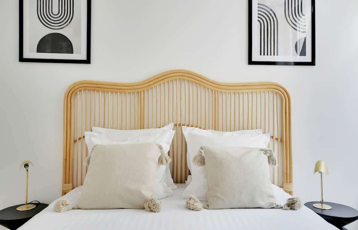 A bed with a wooden headboard, two bedside tables, and two framed abstract artworks on the wall.