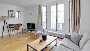 Una sala de estar moderna con un sofá, una mesa de centro, un televisor, una silla y un escritorio.