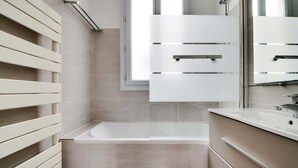Ein modernes Badezimmer mit einer Badewanne, einem großen Spiegel und einem Fenster.