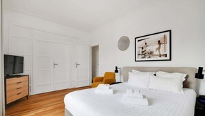 Ein Hotelzimmer mit einem großen Bett, einem Fernseher, einem Kleiderschrank und einem gerahmten Bild an der Wand.