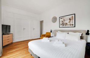 A hotel room with a large bed, a TV, a wardrobe, and a framed picture on the wall. - A Stunning 1-BR in Saint Michel Notre Dame (Paris)