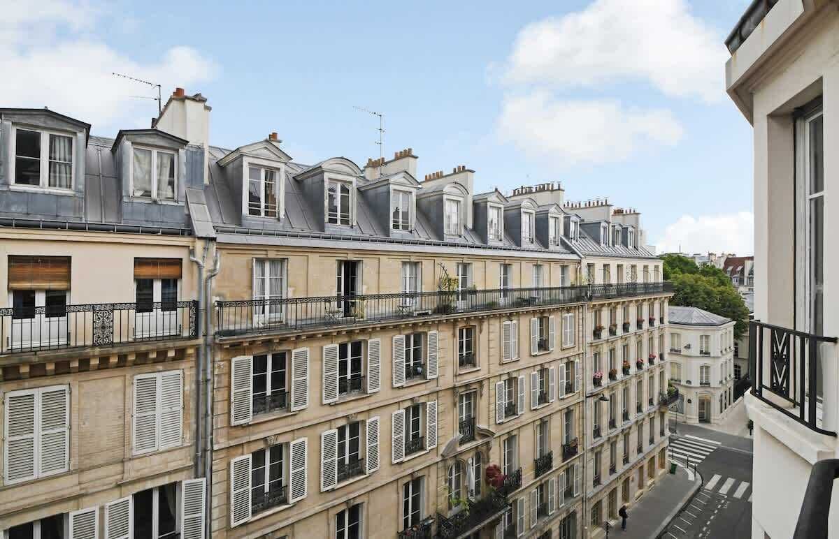 A row of classic European townhouses with multiple stories, balconies, and a uniform architectural style.
