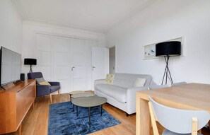 Ein modernes Wohnzimmer mit Sofa, Couchtisch, Fernseher und Essbereich.